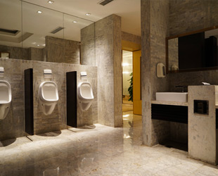 interno di toilette pubblica con urinatoi e lavandini