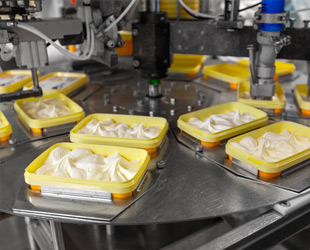 macchina industriale mentre riempie vaschette di gelato