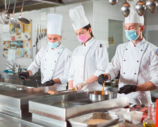 tre cuochi a lavoro in cucina di ristorante