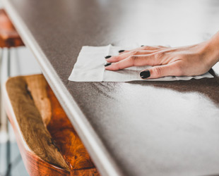 mano di donna mentre pulisce il tavolo con un panno