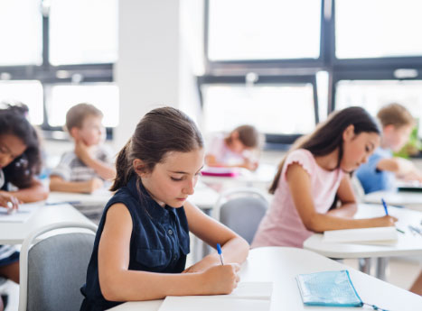 due bambine in classe mentre scrivono un tema