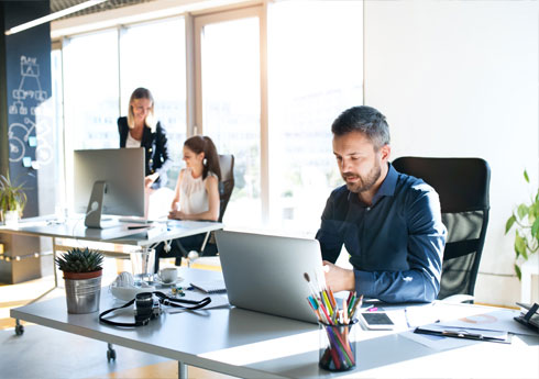 uomo e due donne in ufficio mentre usano il pc